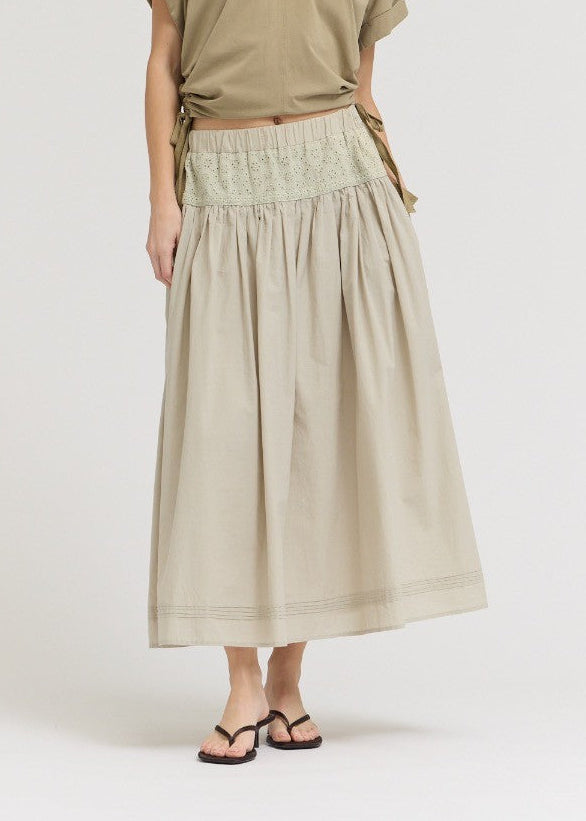 Woman wearing a beige top and skirt on a white background