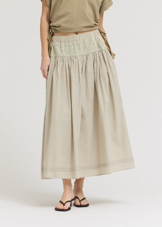 Woman wearing a beige top and skirt on a white background