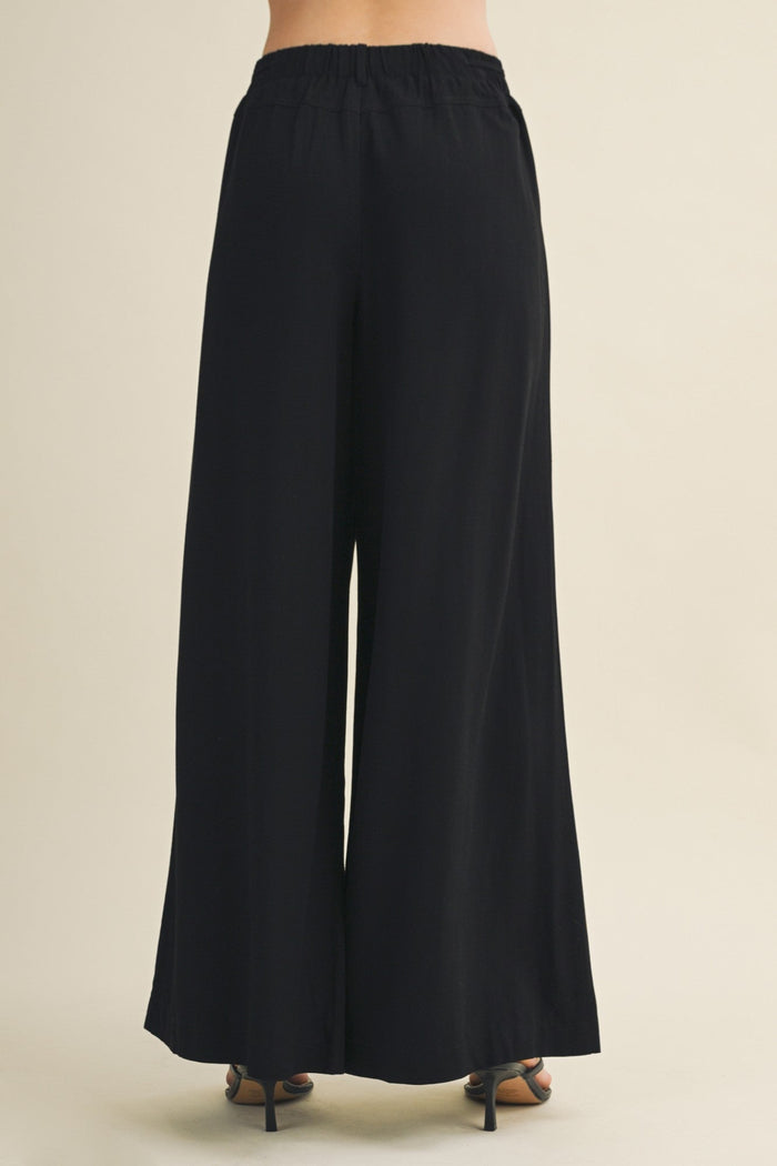 Black wide-leg pants on a beige background