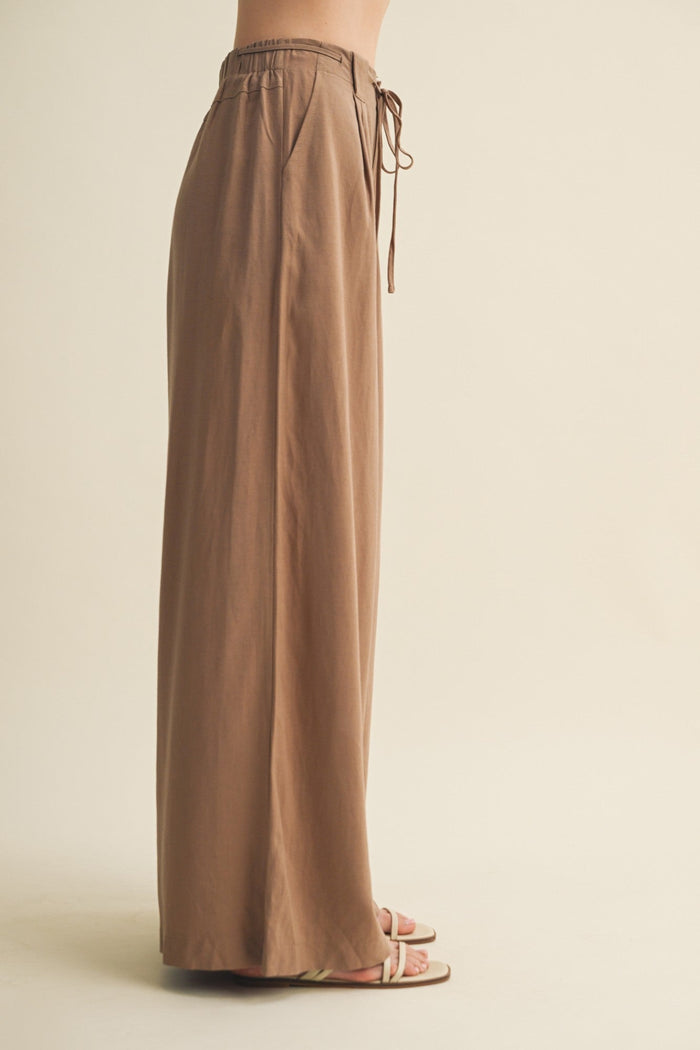 Brown wide-leg pants with a drawstring waist on a beige background