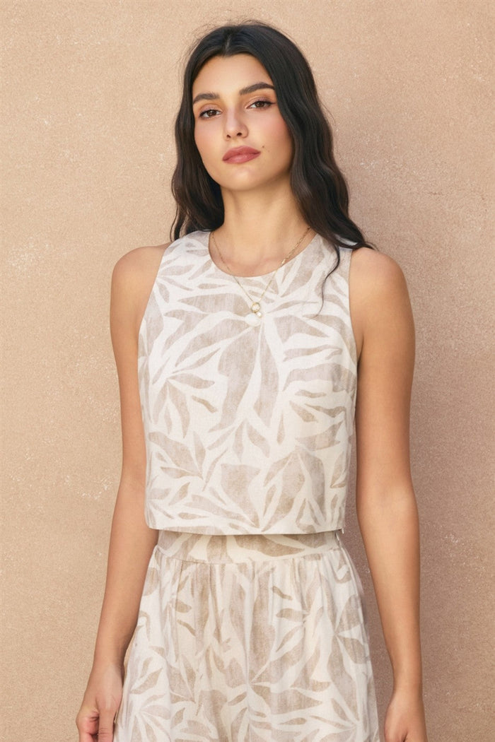 Sleeveless cream tank top with beige leaf print and tie-back detail at neckline.