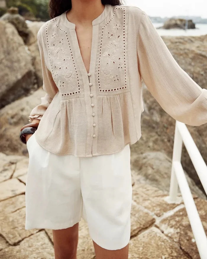 Cream long sleeve top with eyelet embroidery on front panel, button front closure, and gathered waist detail.