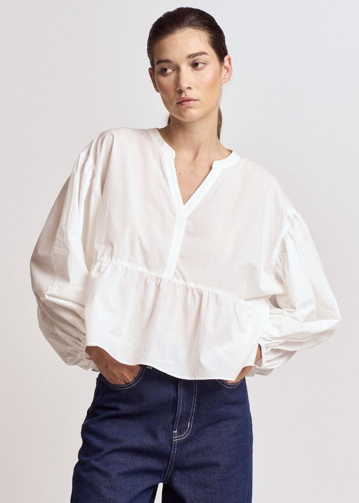 White blouse with voluminous balloon sleeves, V-neckline, and gathered waist detail.