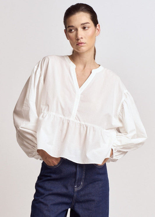 White blouse with voluminous balloon sleeves, V-neckline, and gathered waist detail.