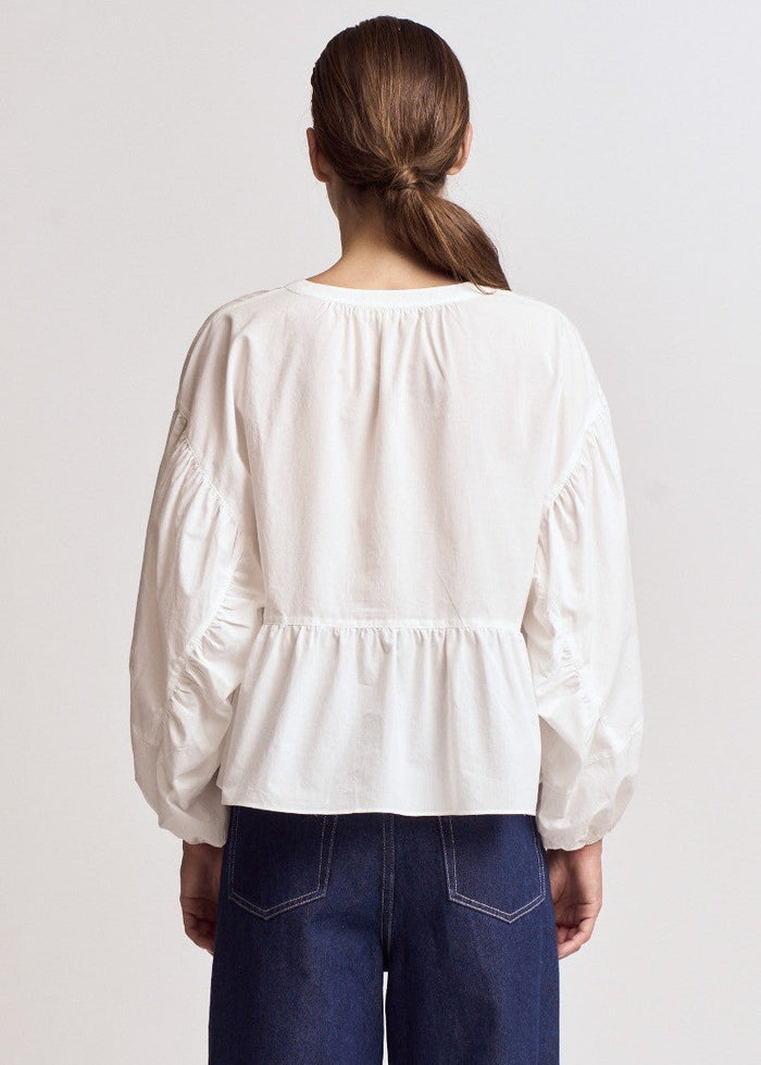 White cotton blouse with gathered balloon sleeves and ruched waist detail, shown from back view.