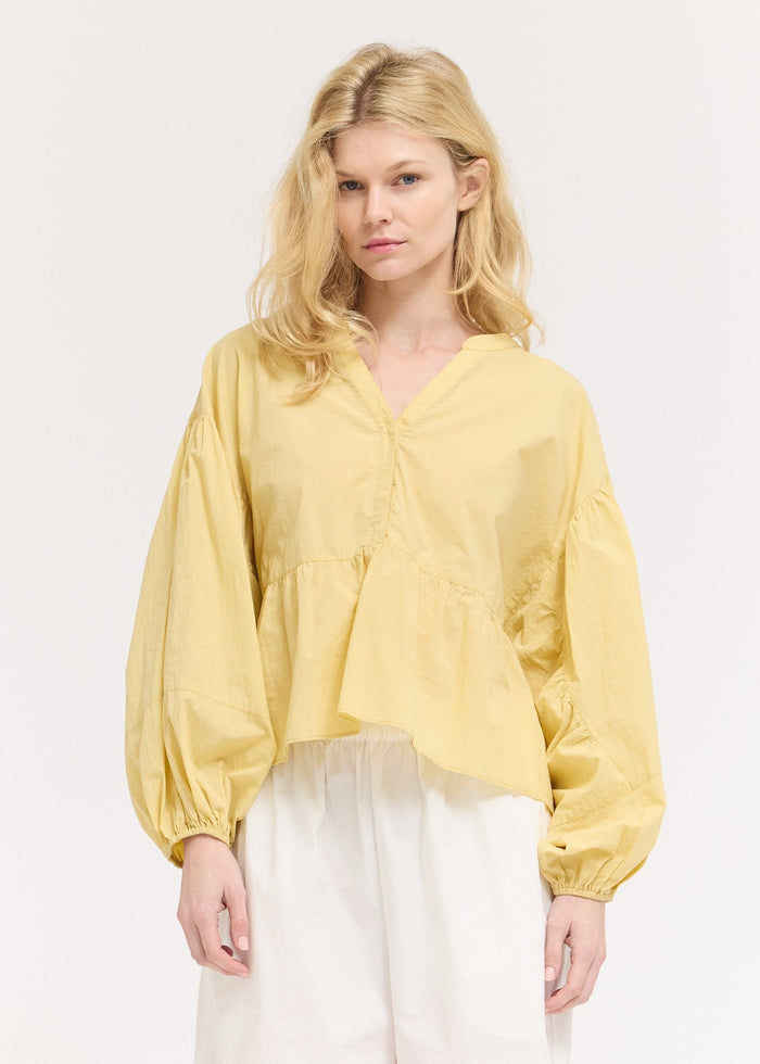 Yellow blouse with voluminous balloon sleeves, V-neckline, and button front closure.