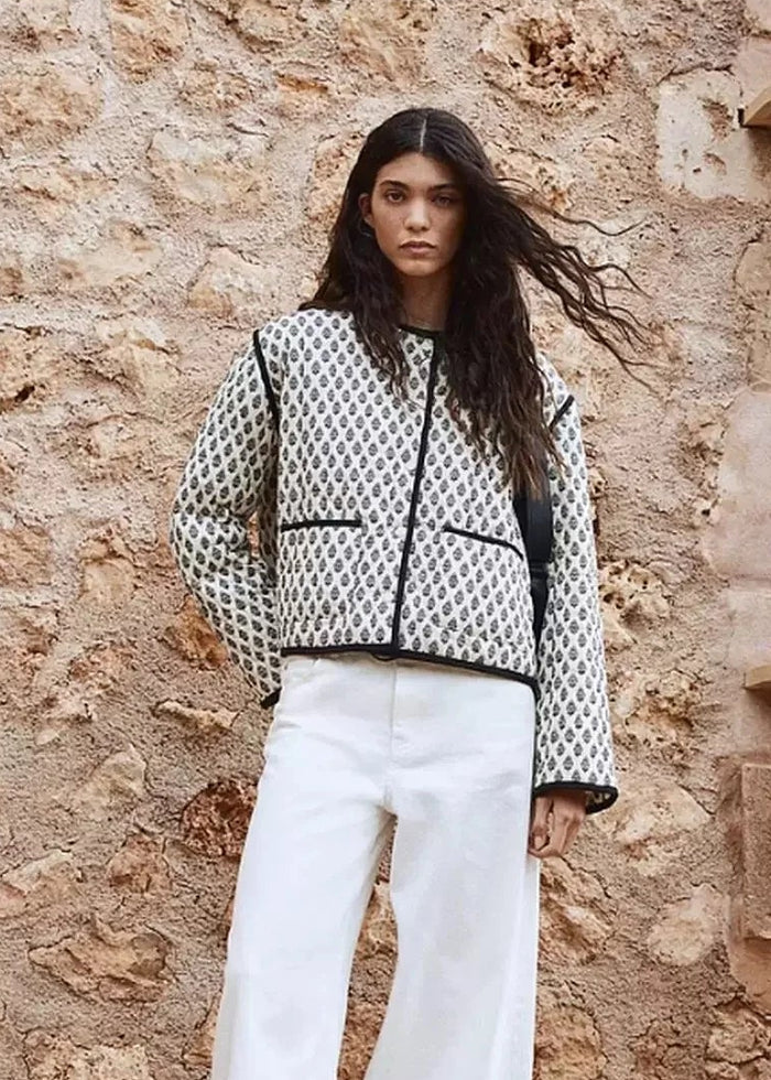 Cropped quilted jacket with white and navy geometric pattern, black trim, and zip front closure.