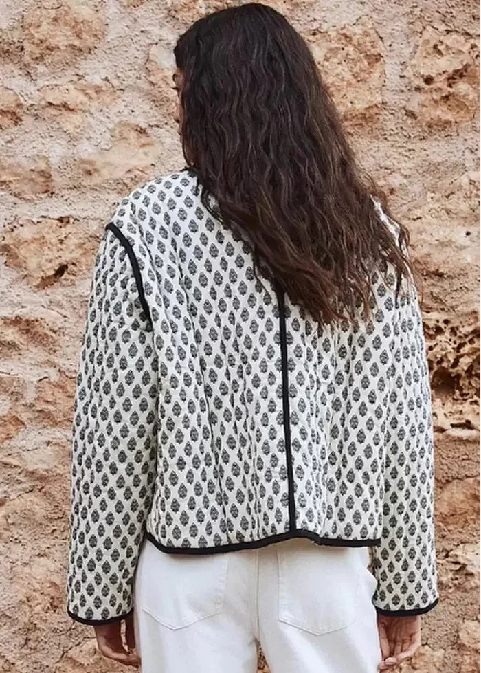 White quilted jacket with black diamond pattern and trim, cropped length, shown from back view.
