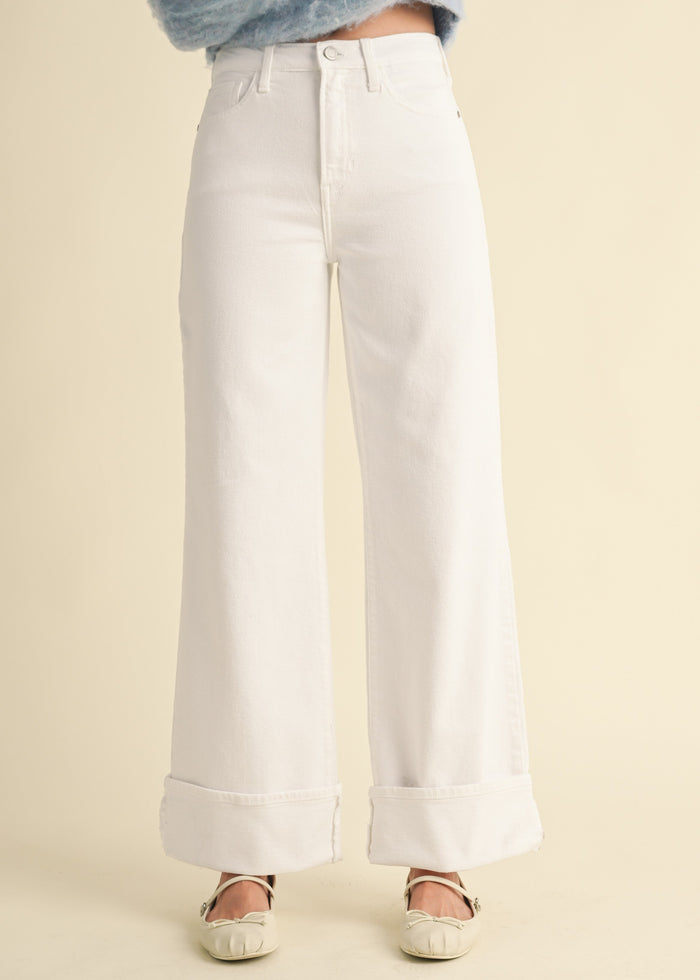 White wide-leg palazzo jeans with high rise and rolled cuffs at ankles.