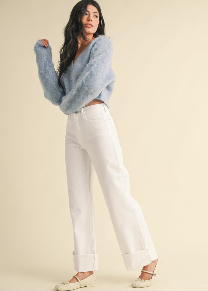 White palazzo jeans with wide-leg silhouette and cuffed ankles, styled with a light blue fuzzy sweater.