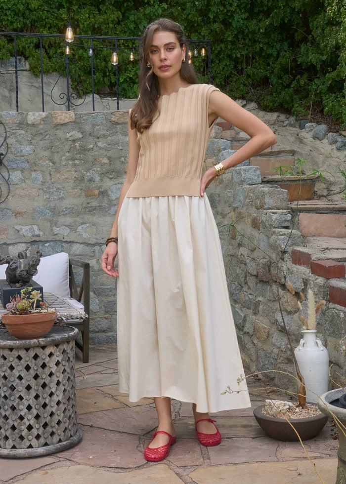 Sleeveless midi dress with beige ribbed top and cream pleated skirt, worn with red quilted flats.