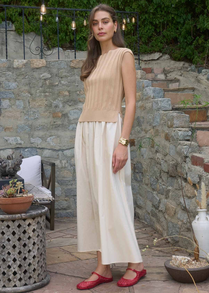 Sleeveless midi dress with beige ribbed top and cream pleated skirt, modeled with red flat shoes.