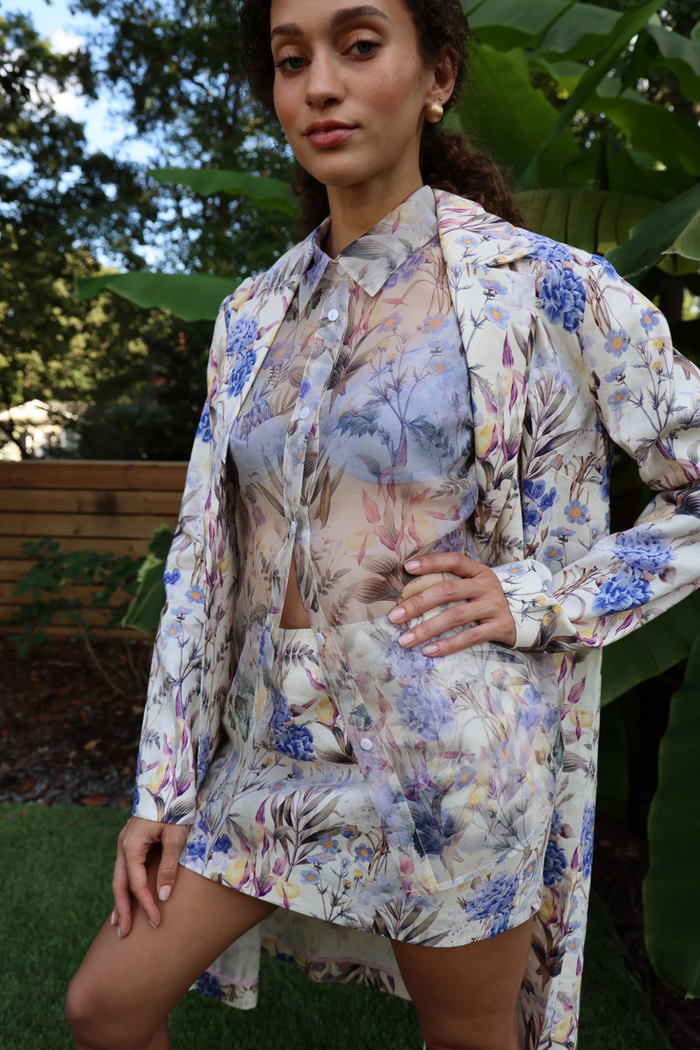 Woman wearing cream linen shirt with blue, purple, and pink floral print over matching skirt.
