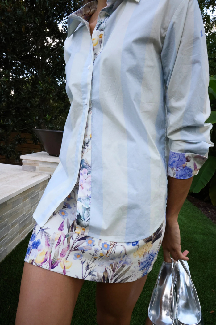 White linen skirt with multicolored floral print, knee-length, worn with white button-up shirt.