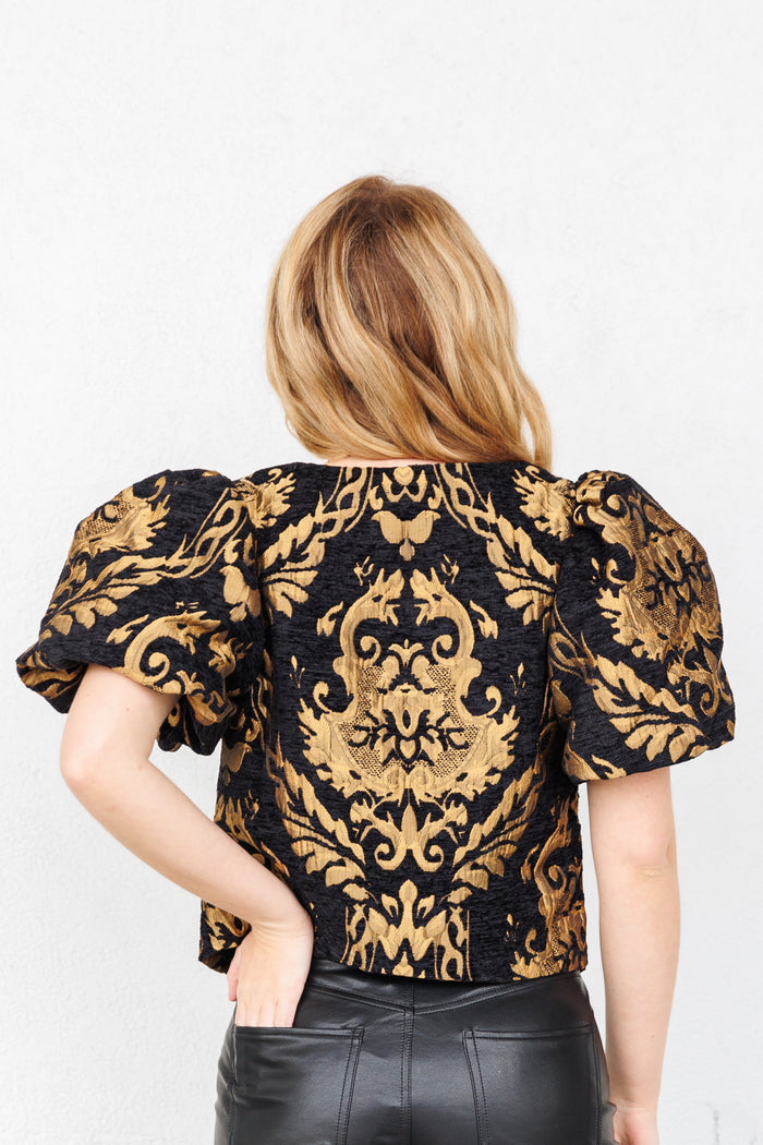 Black and gold jacquard top with puffed short sleeves and ornate damask pattern, shown from back.