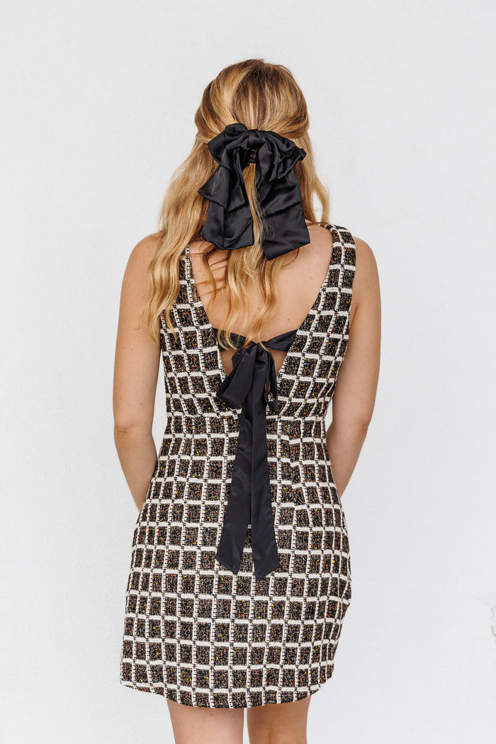 Black and white checkered mini dress with open back and black bow tie detail.