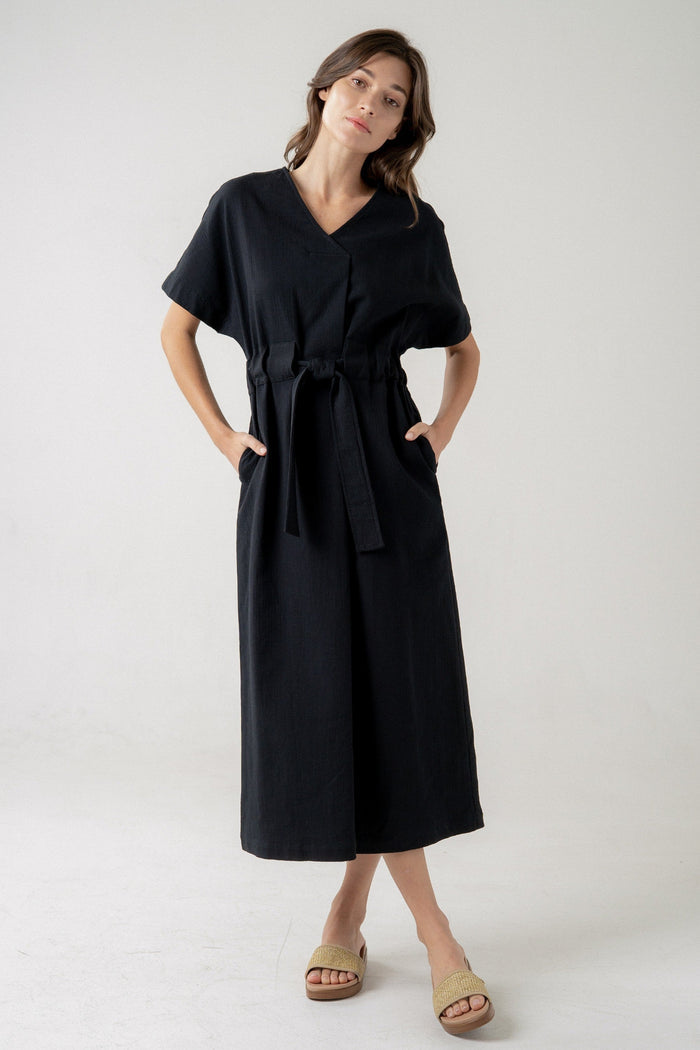 Black midi dress with V-neckline, short sleeves, tie waist, and front pockets.