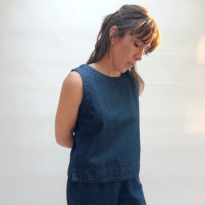 Woman wearing a blue sleeveless top against a white background