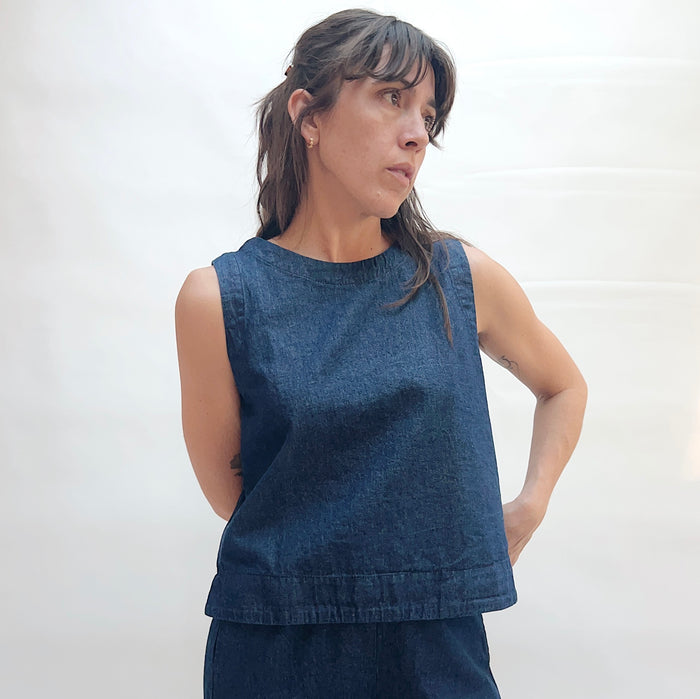 Woman wearing a blue sleeveless top against a white background