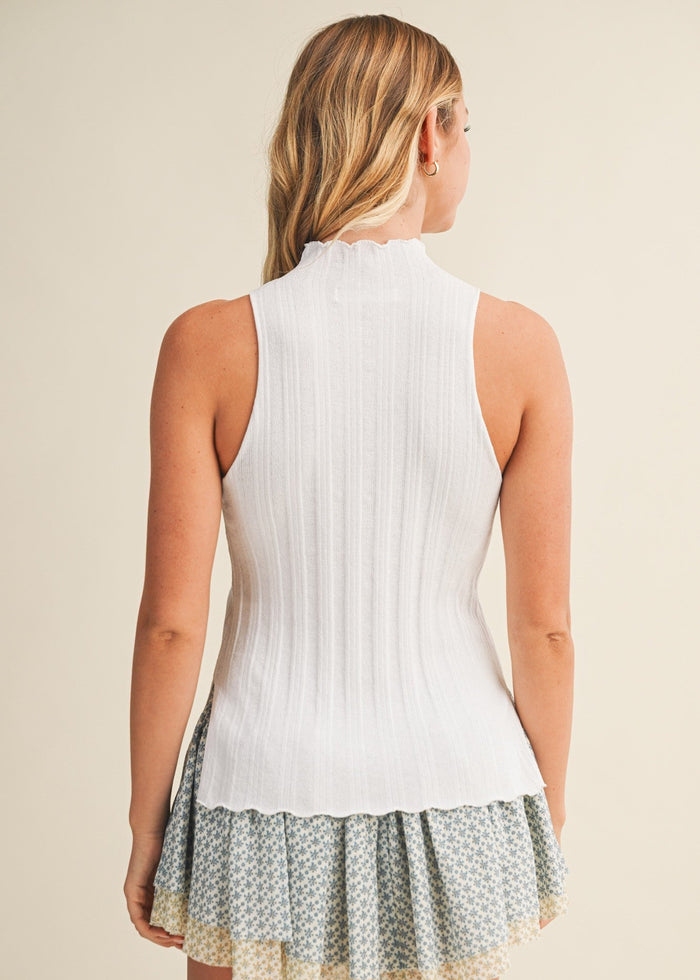 White ribbed sleeveless top with side slit, paired with patterned tiered skirt in sage and cream tones.