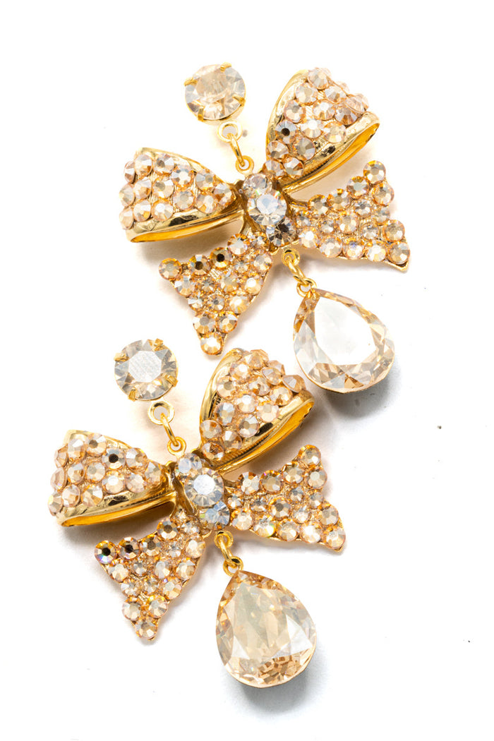 Gold bow-shaped earrings with crystal accents on a white background