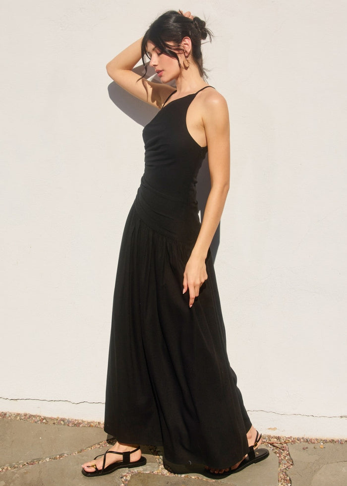 Black sleeveless maxi dress with ruched drop waist and gathered skirt hem.