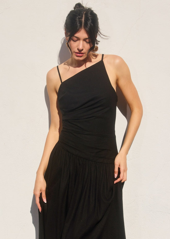 Black maxi dress with asymmetrical neckline, thin straps, ruched bodice, and gathered skirt at drop waist.