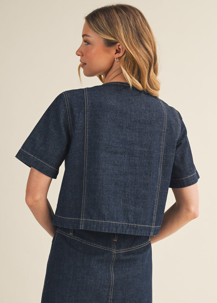Woman wearing a blue denim dress against a beige background