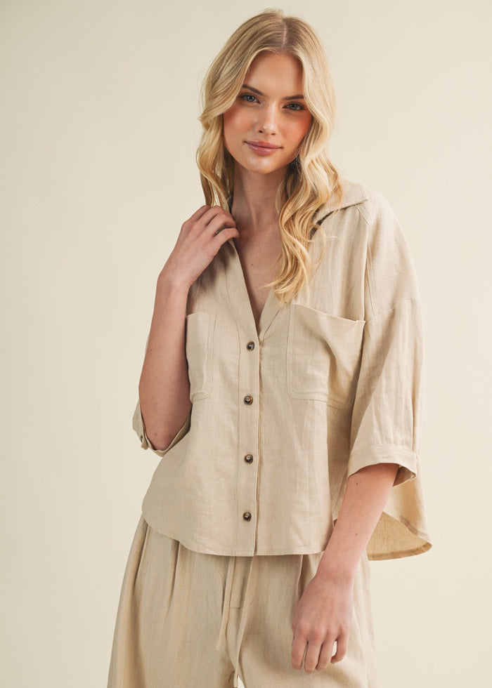 Cream linen button-up top with three-quarter sleeves, collar, and chest pockets worn with matching skirt.