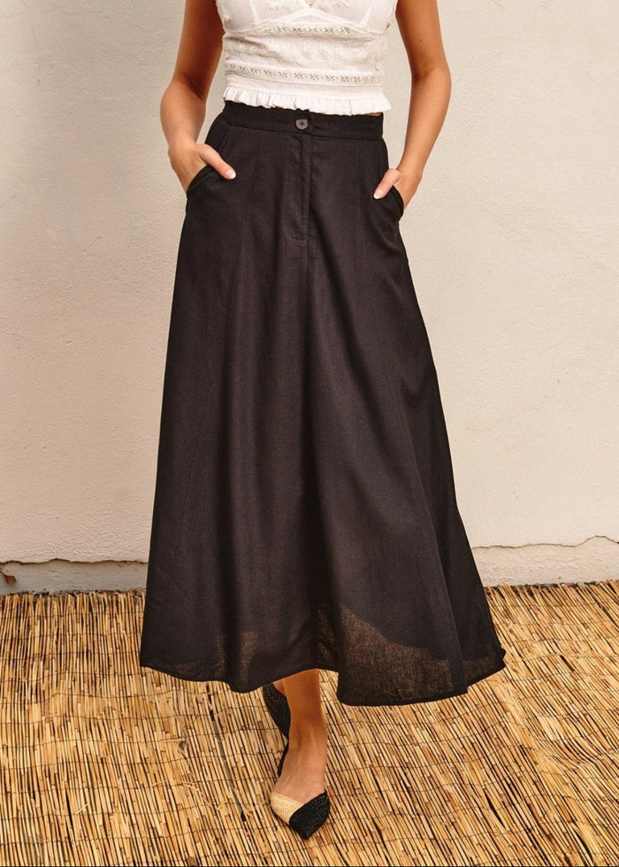 Black flared maxi skirt with button waistband and side pockets, worn with white embellished top.