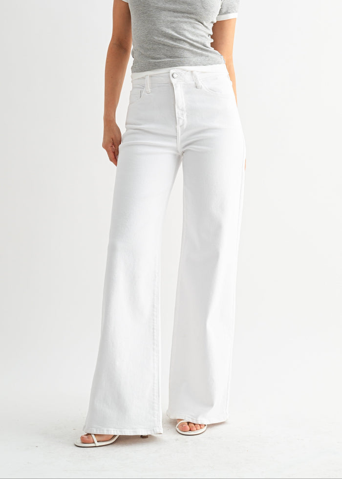 White wide-leg jeans with high waist and button fly, paired with gray t-shirt and white slide sandals.