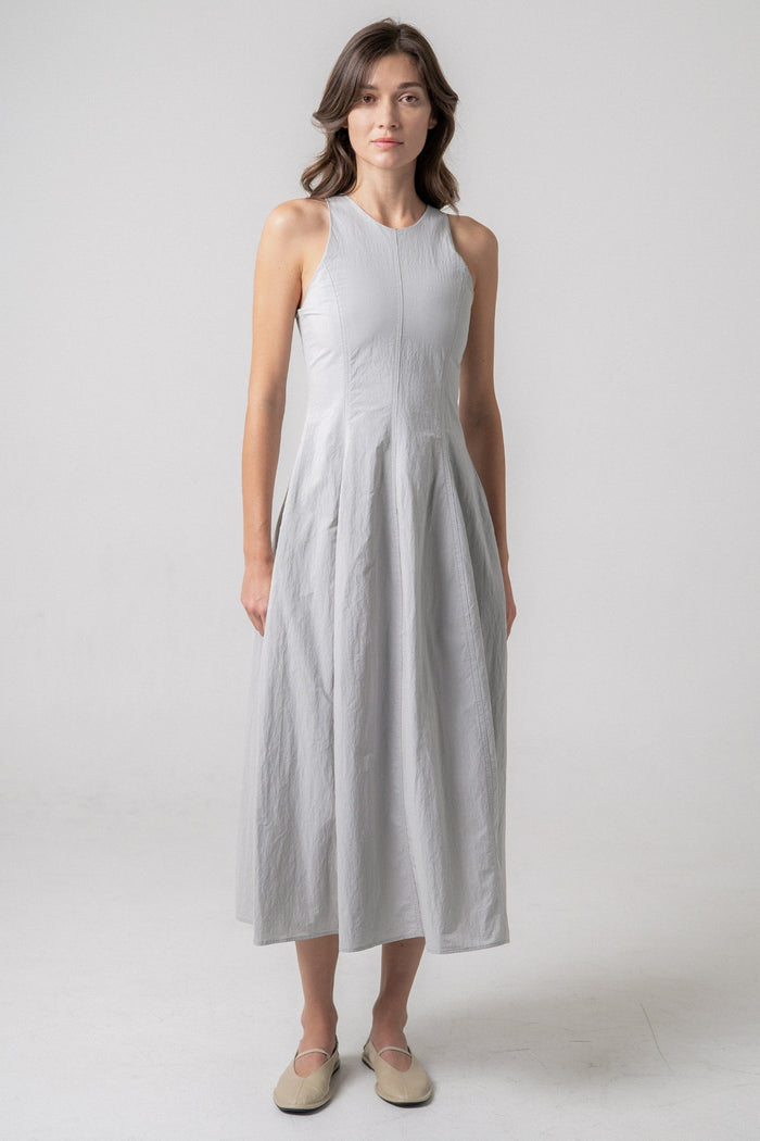 Light gray sleeveless midi dress with a fitted bodice and flared skirt, worn with neutral flat shoes.