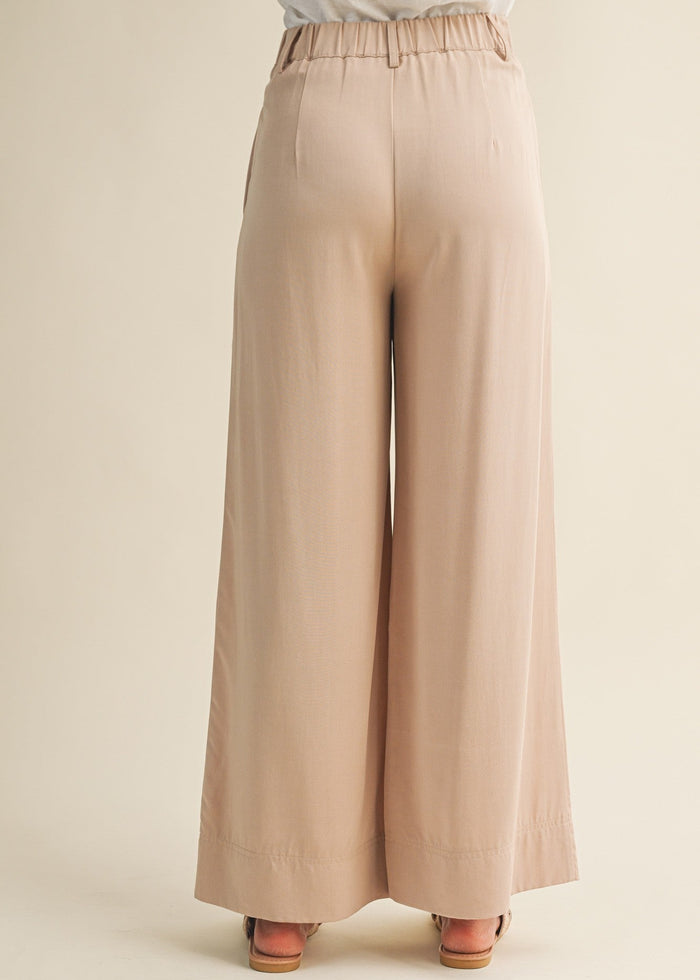 Beige wide-leg pants with elastic waistband, shown from back view on model wearing platform sandals.