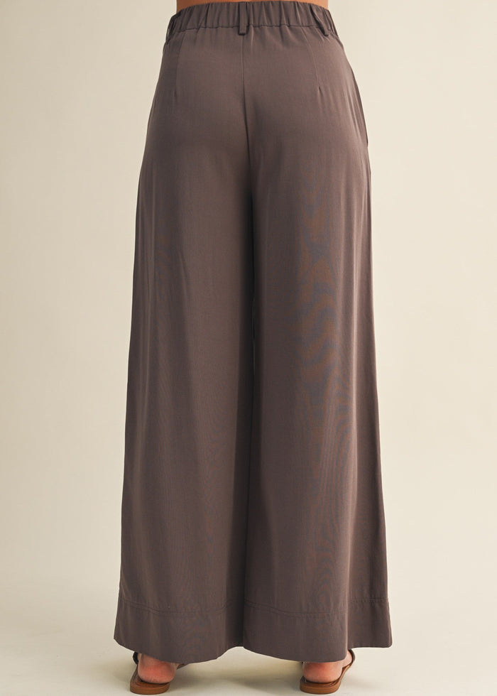 Taupe wide-leg pants with elastic waistband shown from back, ankle-length with relaxed fit.