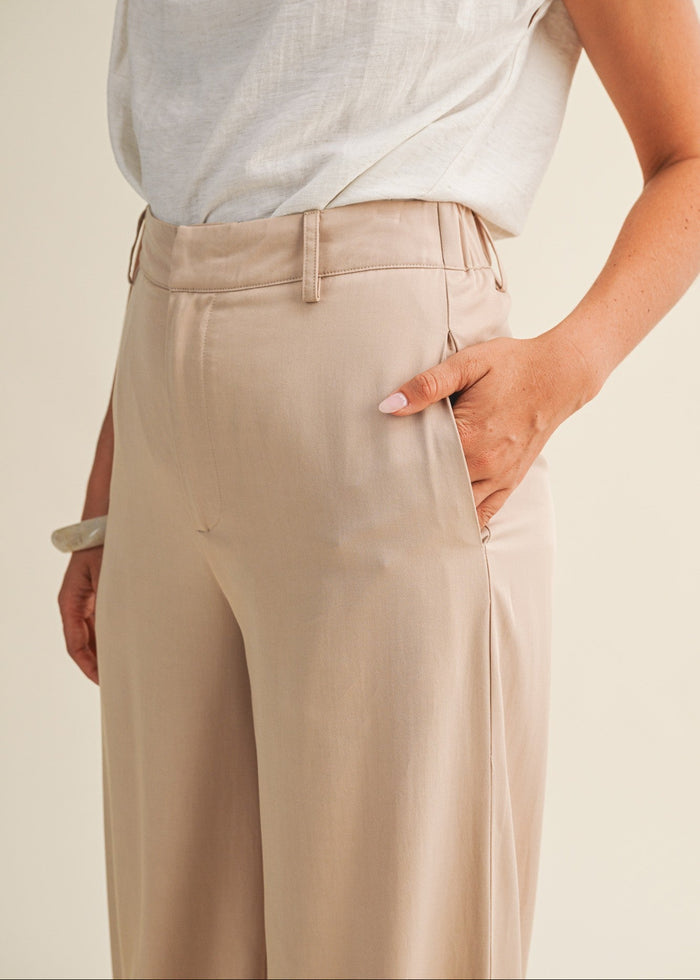 Beige wide-leg pants with belt loops and side pockets, shown with white sleeveless top.