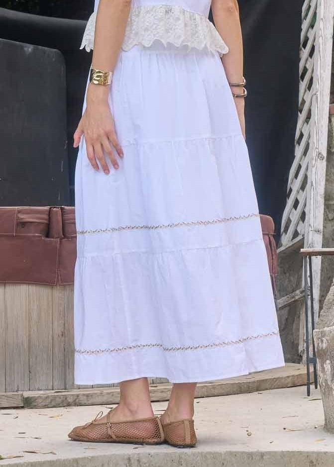 White midi skirt with tiered panels and gold embroidered trim details.
