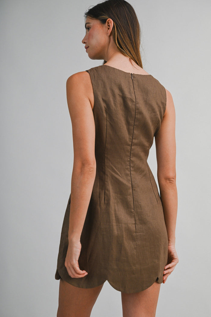 Sleeveless brown linen mini dress with scalloped hem, shown from back view on model.