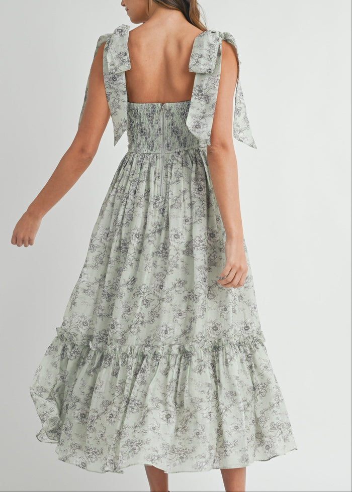 Sage green floral midi dress with ruched bodice, tie-shoulder details, and tiered skirt, shown from back view.