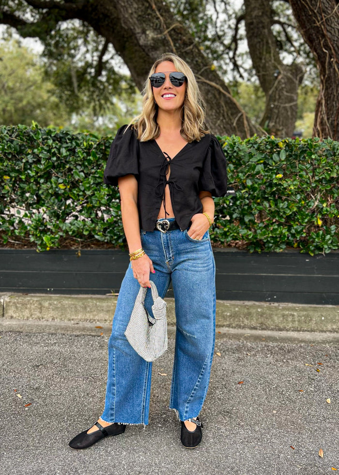 Black short-sleeve top with voluminous bubble sleeves and front tie closure.