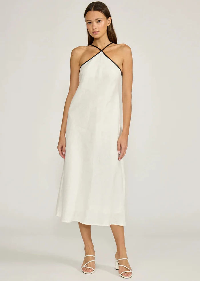 Woman wearing ivory halter midi dress with crossover neckline and strappy white sandals.