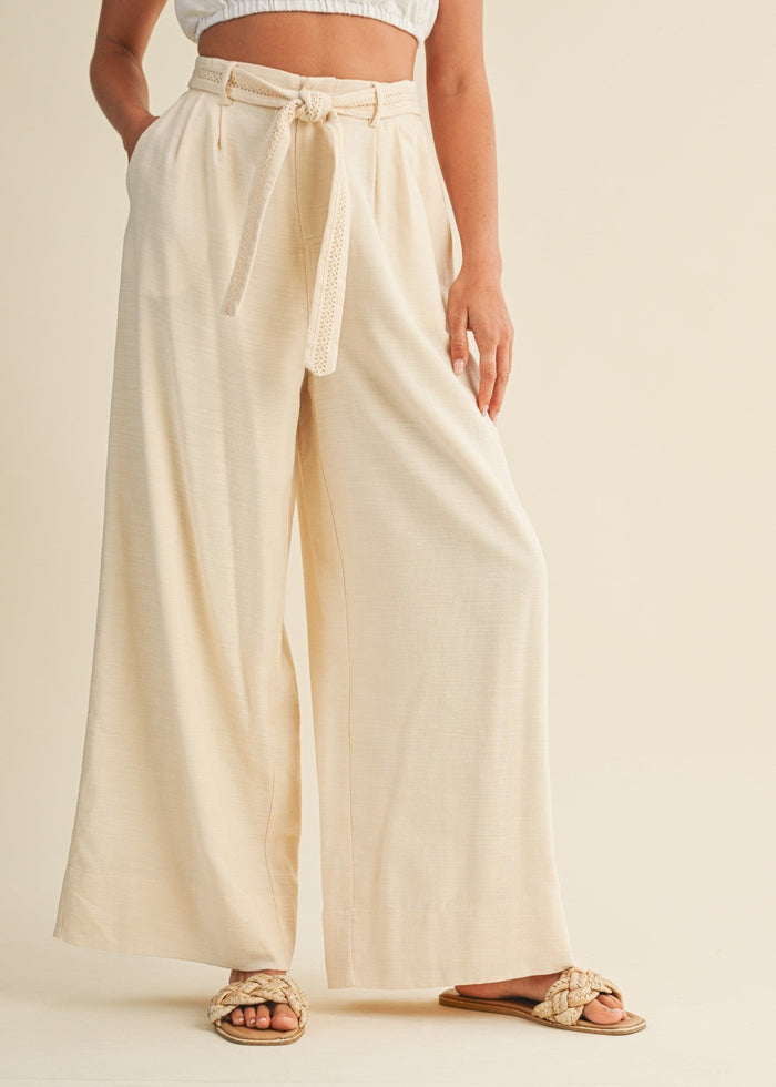 Cream pleated palazzo pants with tie waist belt and side pockets.