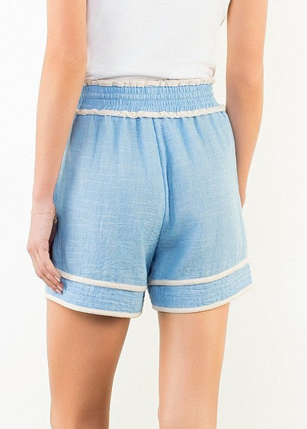 Light blue pull-on shorts with white trim and elastic waistband, worn with white top.