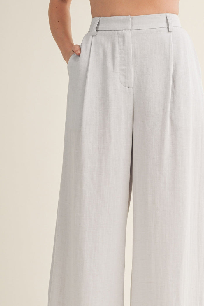 White wide-leg pants with front pleats, high waist, and side pockets.