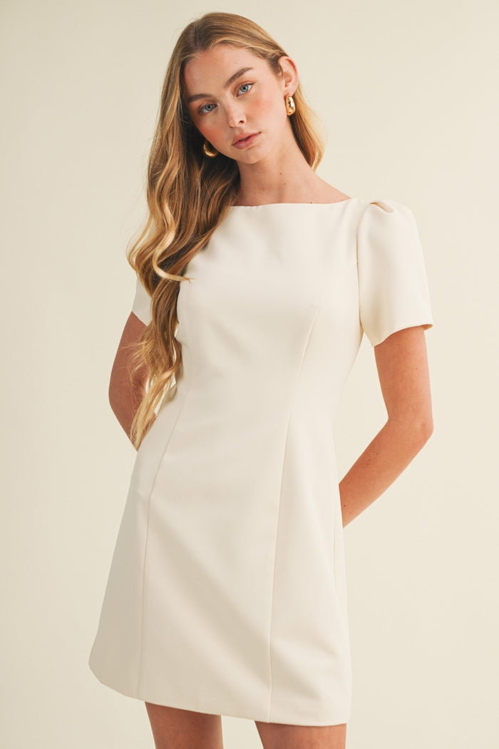 Woman wearing a white dress against a beige background