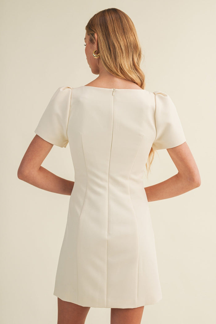Woman wearing a white dress against a beige background