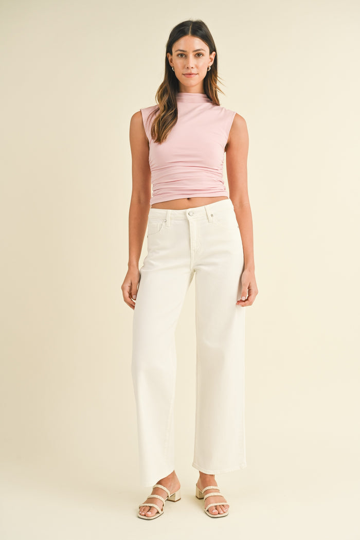 Woman wearing cream-colored wide-leg jeans with high waist and cropped pink sleeveless top.