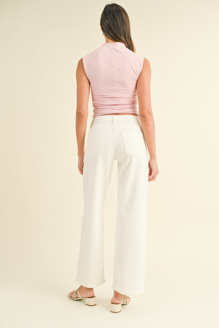 Woman wearing cream wide-leg jeans with high waist and pink sleeveless top, shown from behind.