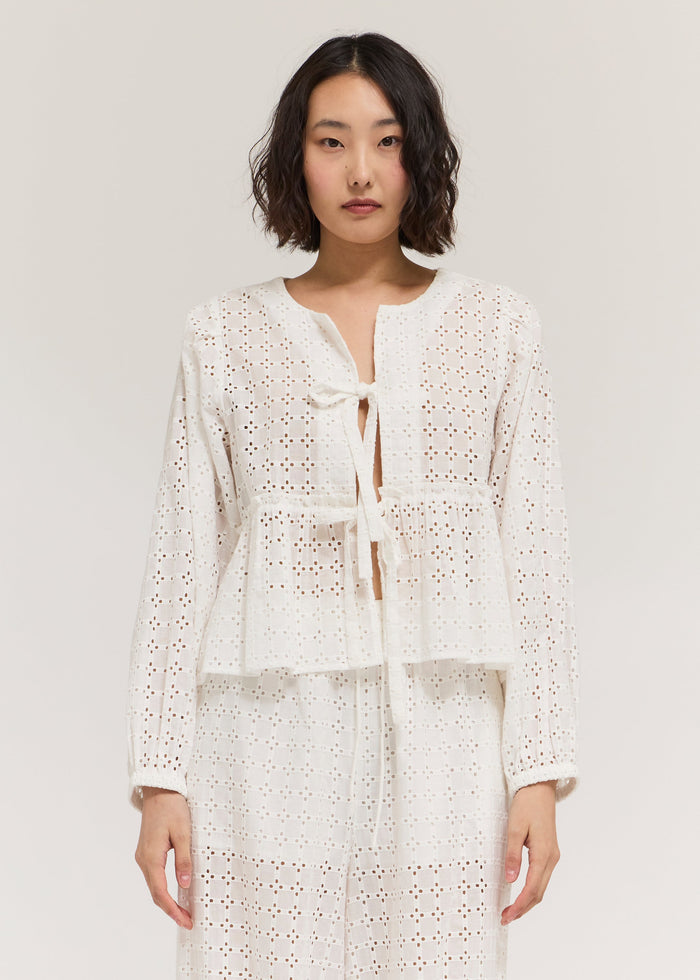 Cream long sleeve top with eyelet pattern and front tie detail.