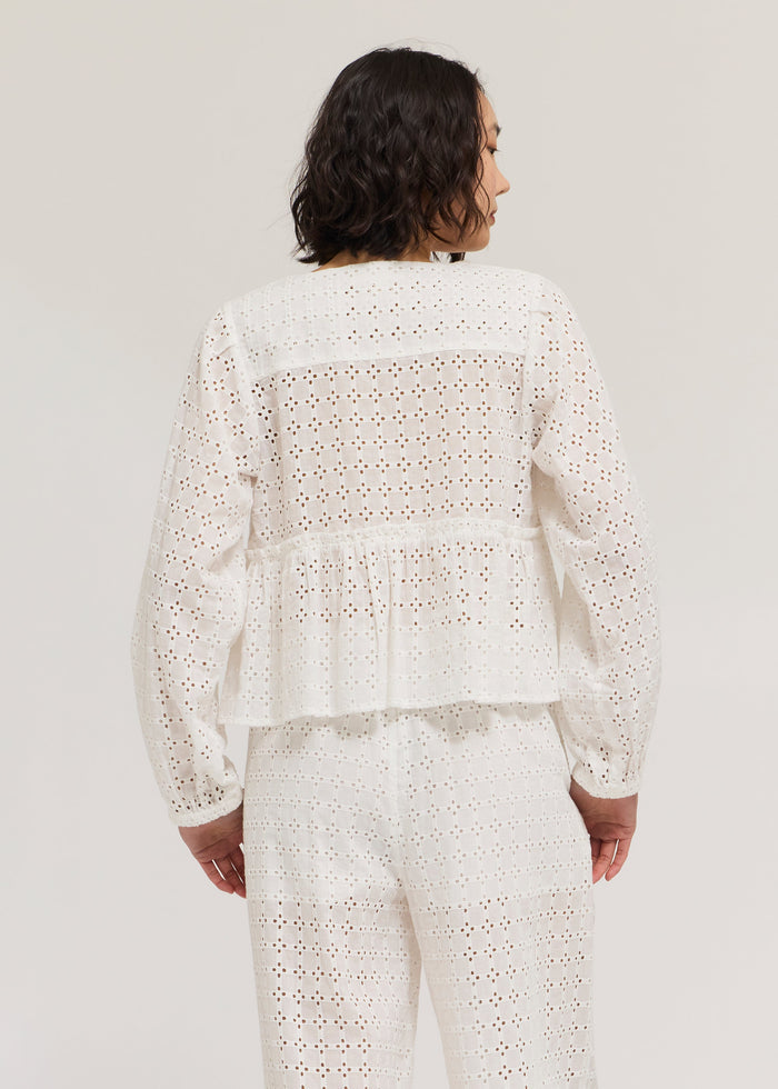 White long sleeve eyelet top with gathered waist and peplum detail, shown from back view.