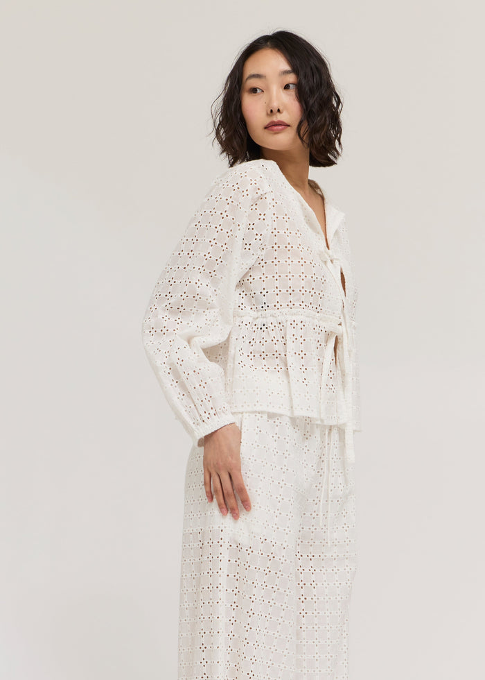 White long sleeve top with eyelet cutout pattern and button front closure.